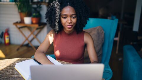 Vorbereitung Eine Frau sitzt an ihrem Laptop und macht sich Notizen